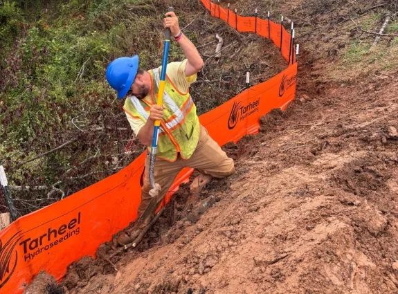 Tarheel Hydroseeding crew member installing orange silt fence